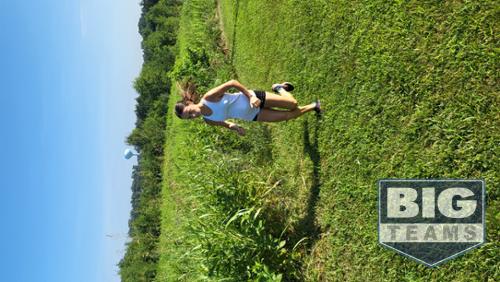 Girl running uphill on grass.