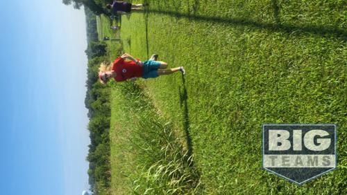 One boy running uphill on grass.